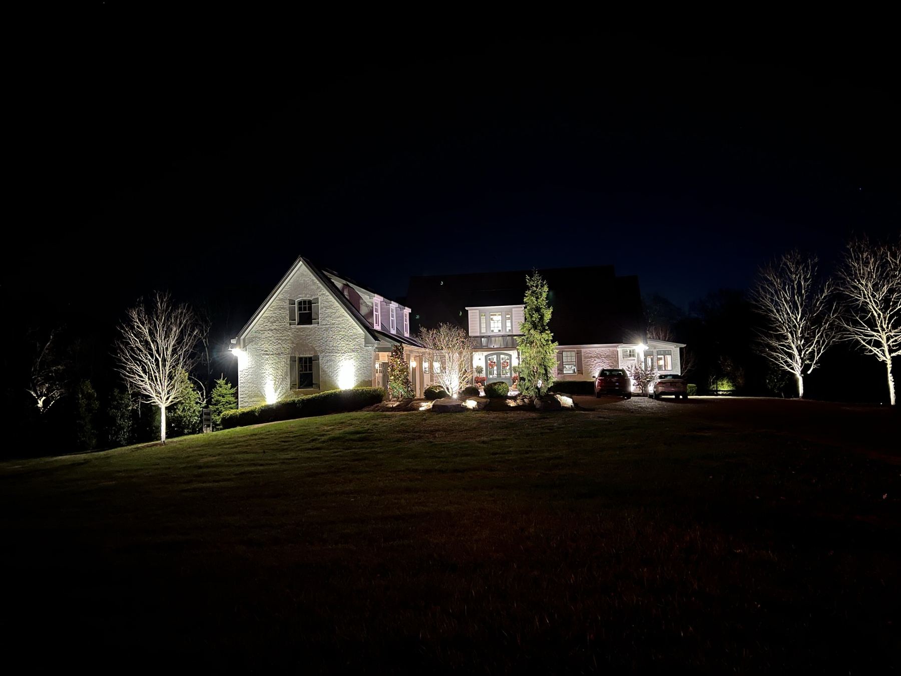 The house lit at night across the lawn